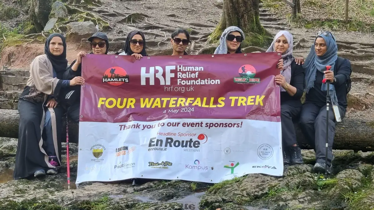 Four Waterfalls Trek women's group holding the Human Relief Foundation sponsorship banner
